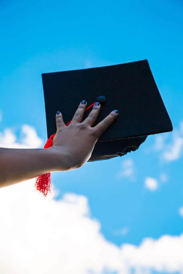 Graduation cap held against the sky, representing public credential verification